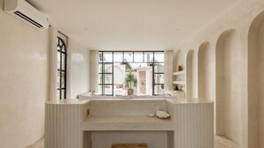 A minimalist bathroom with a large window, a built-in bench, and a shelf with toiletries. - Luxe & Unique honeymoon Bocami Suites- 2 by OriVista (Kerobokan)