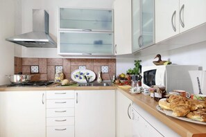 A kitchen with white cabinets, a microwave, a stove, and a sink.