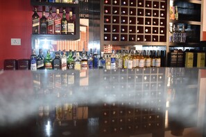 Un bar avec des étagères remplies de bouteilles d’alcool et un mur miroitant qui reflète l’espace bar.
