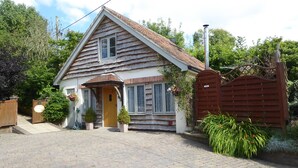 Une maison à deux étages avec un toit en pente, un porche à l’avant et un portail en bois.