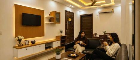 A modern living room with a flat-screen TV, a coffee table, and two leather sofas.