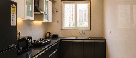 A compact kitchen with a gas stove, a sink, and a window overlooking a residential area.