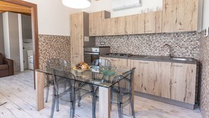 A modern kitchen with wooden cabinets, a glass dining table, and a tiled backsplash. - VILLA SICILY SWIMMING POOL (italia,sicilia)
