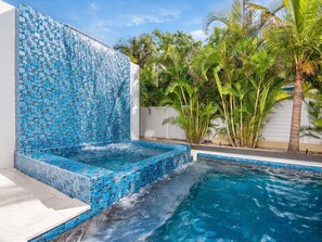 A swimming pool with a mosaic tile wall and palm trees.