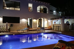 Une piscine avec deux chaises longues, une plante en pot et un escalier menant à un balcon.