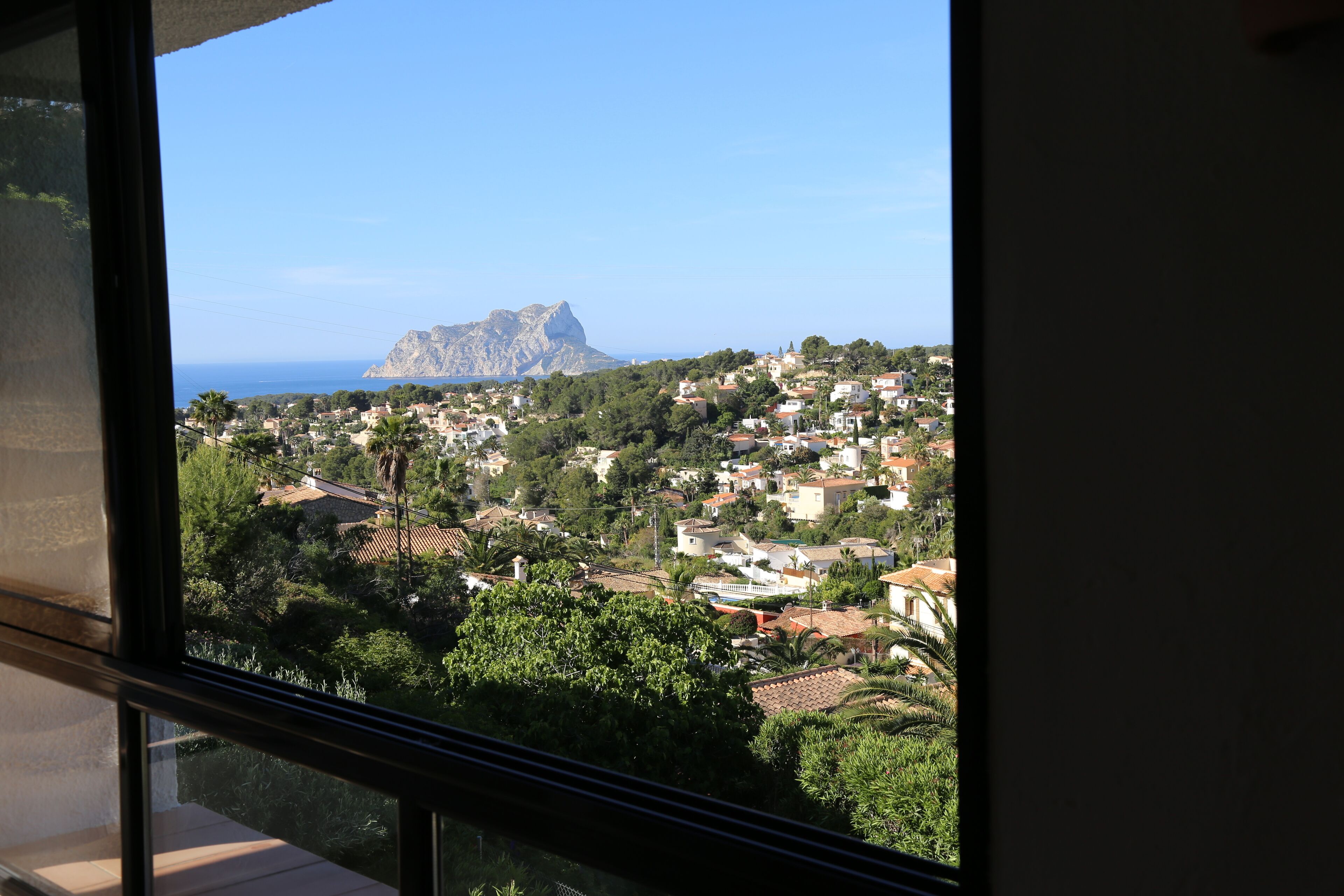Eine Küstenstadt mit einem markanten Berg im Hintergrund, Blick vom Fenster.
