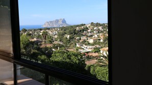 A coastal town with a prominent mountain in the background, viewed from a window.