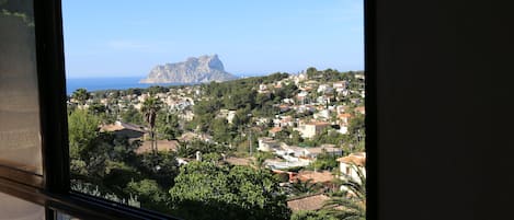 A coastal town with a prominent mountain in the background, viewed from a window.