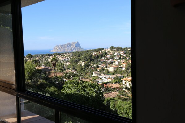 A coastal town with a prominent mountain in the background, viewed from a window.