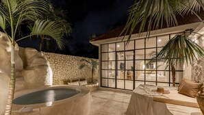 Wellnessbereich mit Whirlpool, Sitzgelegenheiten und Palmen.