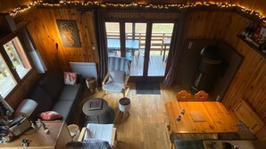 L’intérieur chaleureux d’un chalet avec un plancher en bois, un canapé, une table à manger et une cheminée.