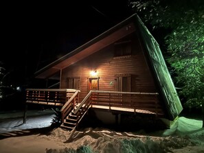 Une cabane en bois avec un escalier menant à l’entrée, entourée de neige.