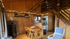 L’intérieur chaleureux d’un chalet avec un coin repas en bois, un canapé, un fauteuil à bascule et une cheminée.