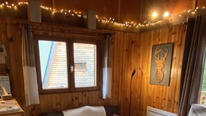 Une pièce chaleureuse avec un décor intérieur en bois, un canapé, deux fauteuils, une petite table et un radiateur.