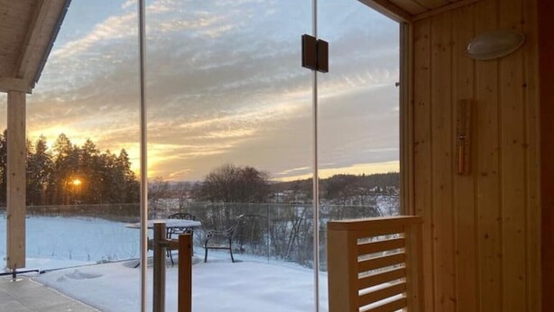 Una cabaña de madera con un vidrio que da a un  área nevada.