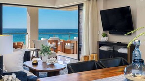 Une chambre d’hôtel moderne dotée d’un balcon, d’une télévision à écran plat et d  ’un coin repas offrant une vue sur la mer.