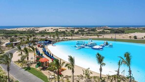 A resort with a large pool, palm trees, and a view of the beach.