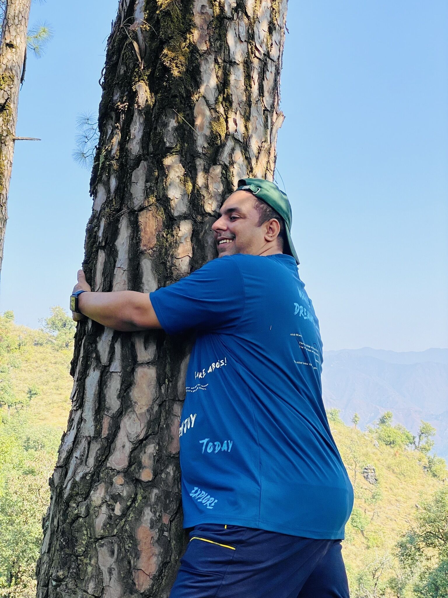 Una persona abrazando el tronco de un árbol al aire libre.