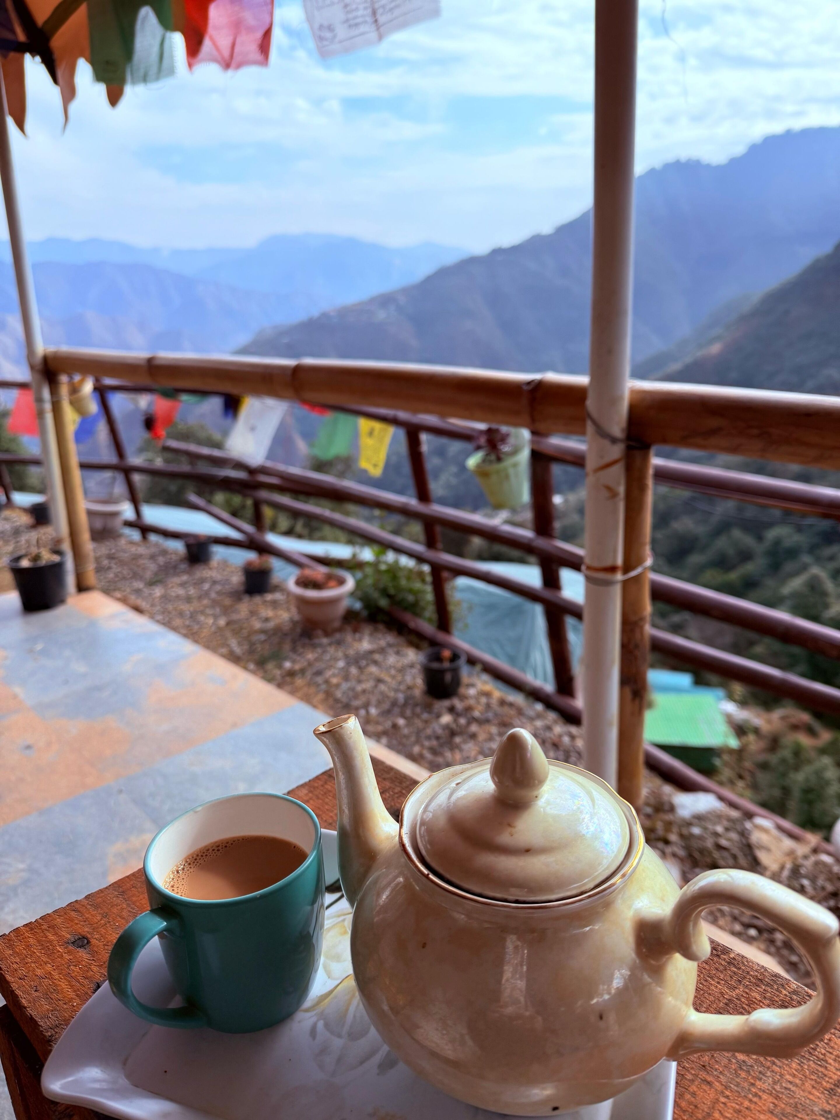 Une théière et une tasse sur une table, avec une vue sur les montagnes en arrière-plan.