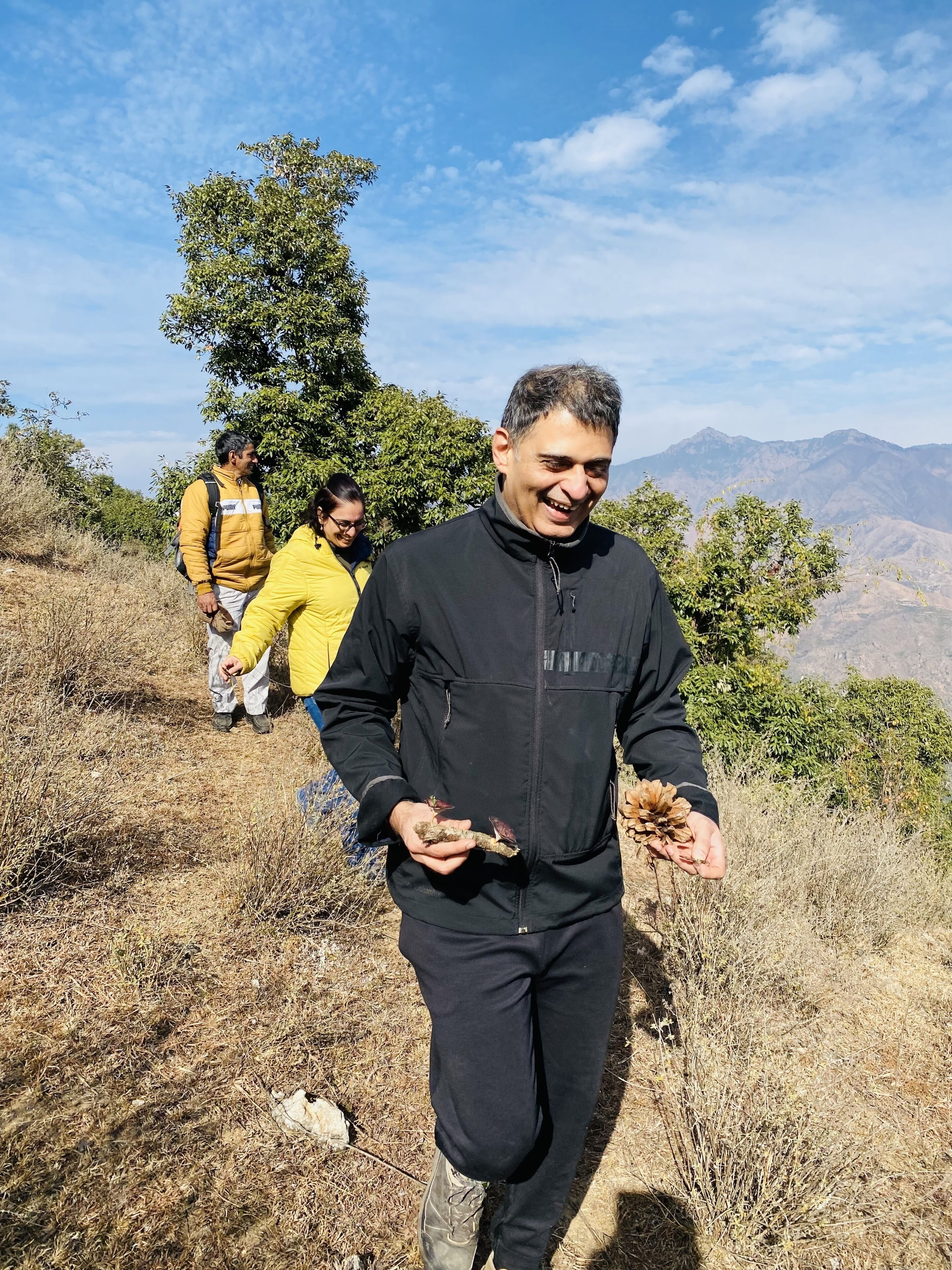 A person walking on a dry, grassy hillside with a mountainous backdrop.
