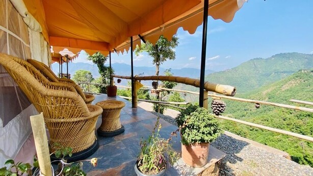 Un espace extérieur aménagé, abrité et doté de meubles en osier, de plantes en pot et offrant une vue panoramique sur les montagnes.