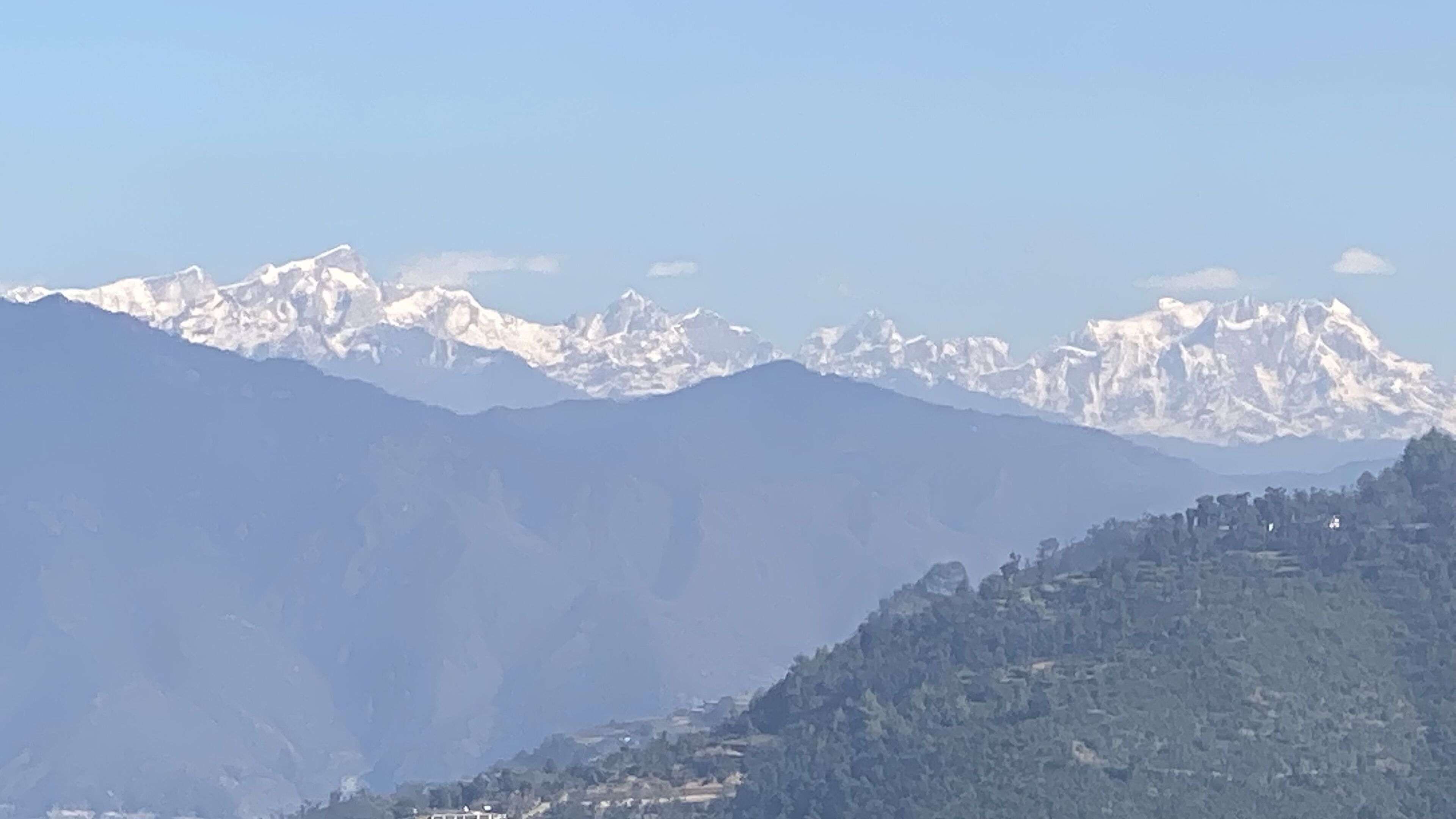 Paisagem montanhosa com picos nevados e um vale com edifícios dispersos.