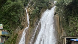 Une cascade se déversant le long d’une falaise rocheuse, entourée d’une végétation luxuriante.