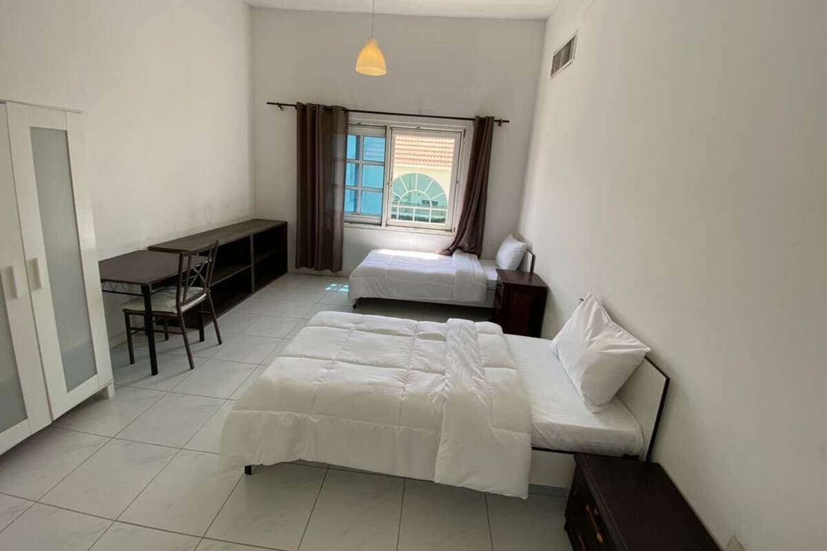 A bedroom with a bed, a desk, and a chair.
