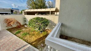 A courtyard with a small garden, a white balustrade, and a building in the background. - Villa 125  (Dubai)