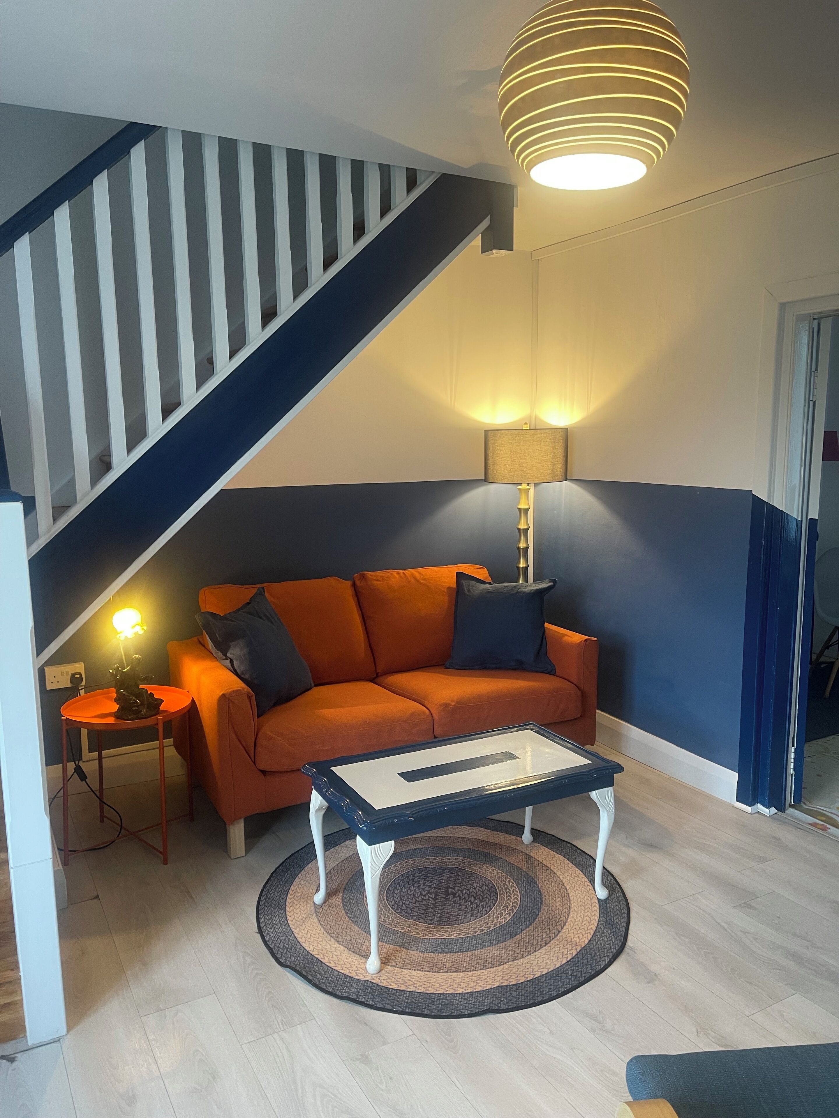 Uma sala de estar moderna com escada, sofá, mesa de centro e abajur.