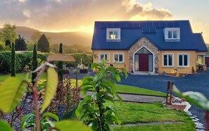 A two-story house with a stone facade, a red door, and a blue roof. - B&B and Self Catering Mon Petit Cottage (Bunclody)