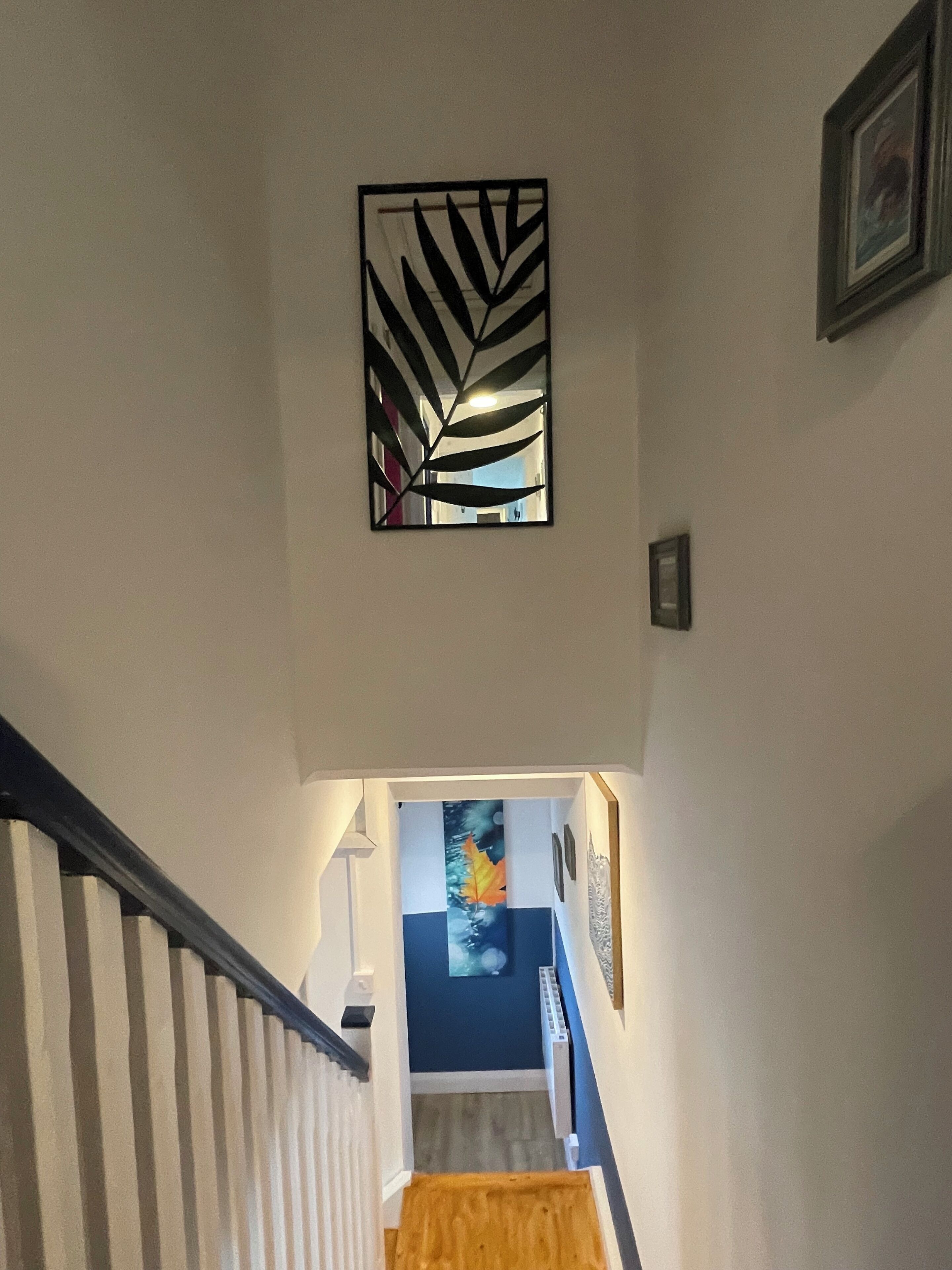 A staircase with a striped handrail, a wall-mounted artwork, and a framed picture.