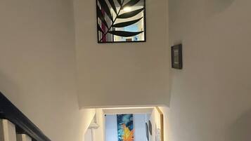 A staircase with a striped handrail, a wall-mounted artwork, and a framed picture.