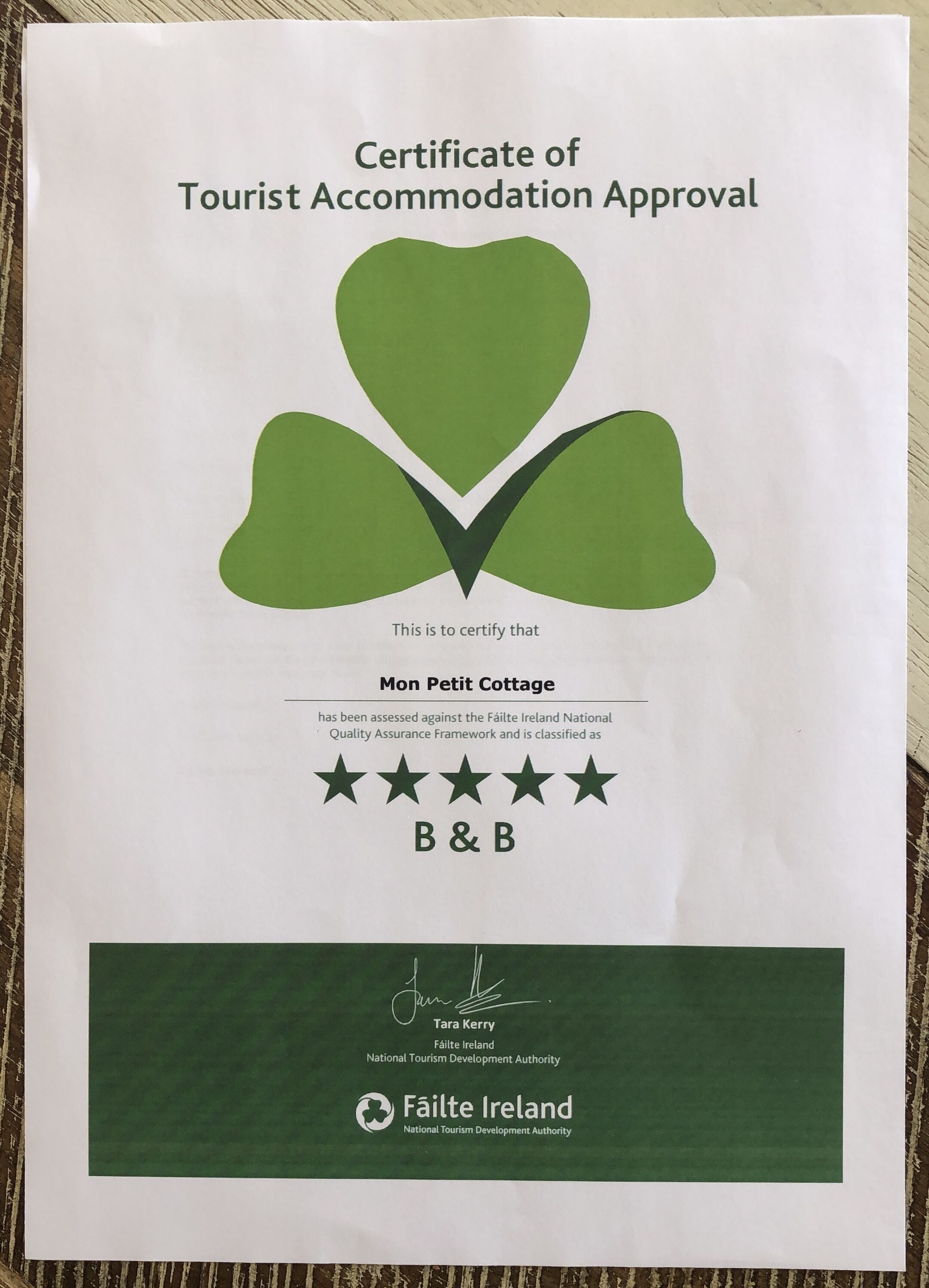 Certificado de aprobación para alojamiento turístico de Mon Petit Cottage, clasificado como casa de huéspedes, con un logotipo verde y firma.