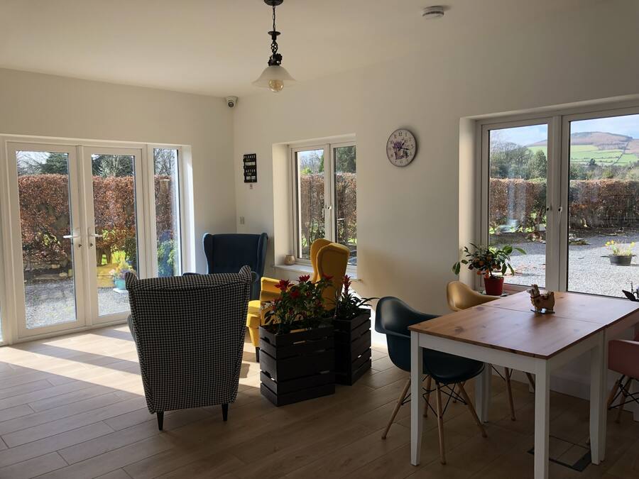 A spacious room with large windows, a dining table, and a variety of chairs.