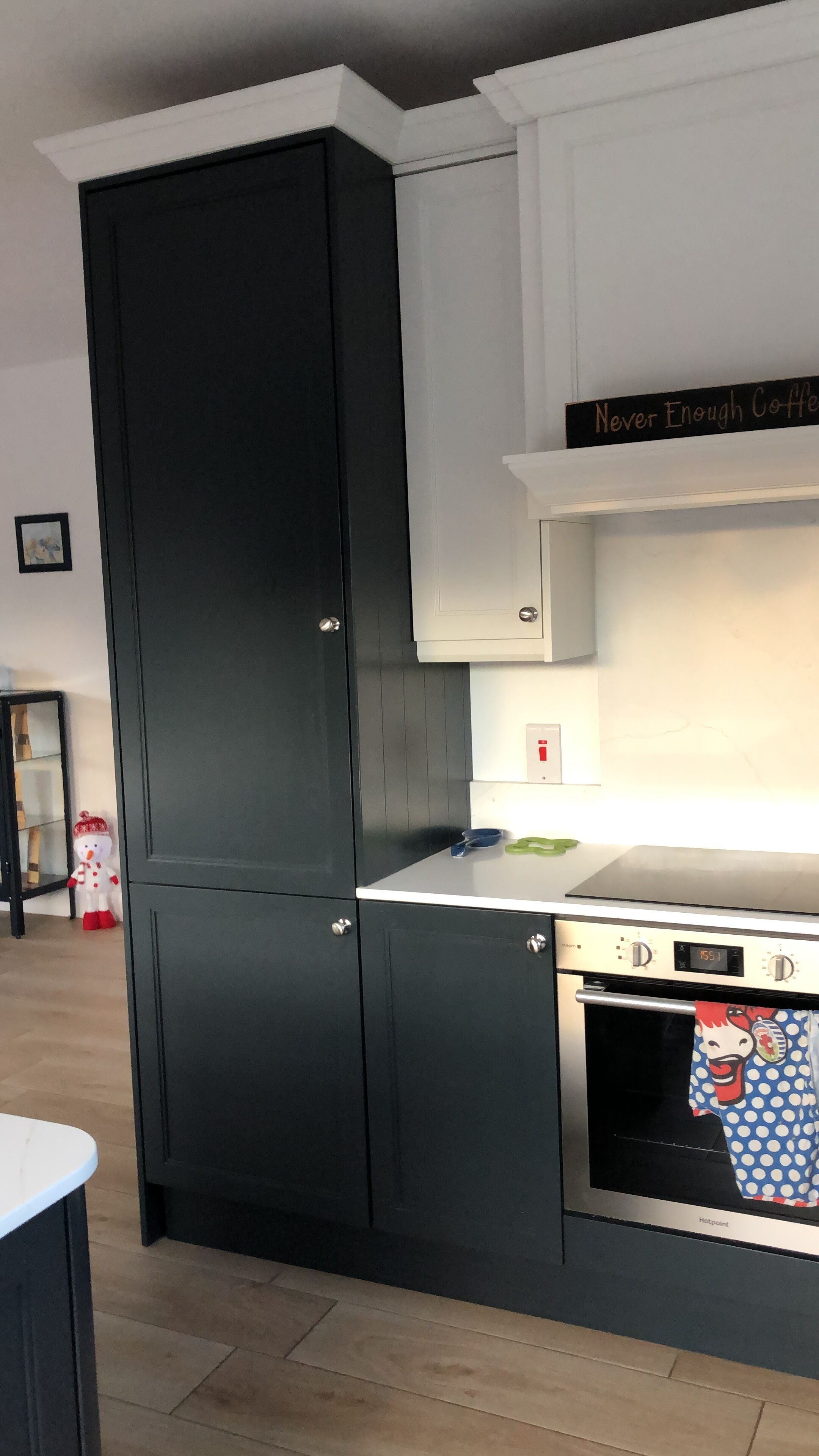 A kitchen with black cabinets, a white countertop, and a stainless steel oven.