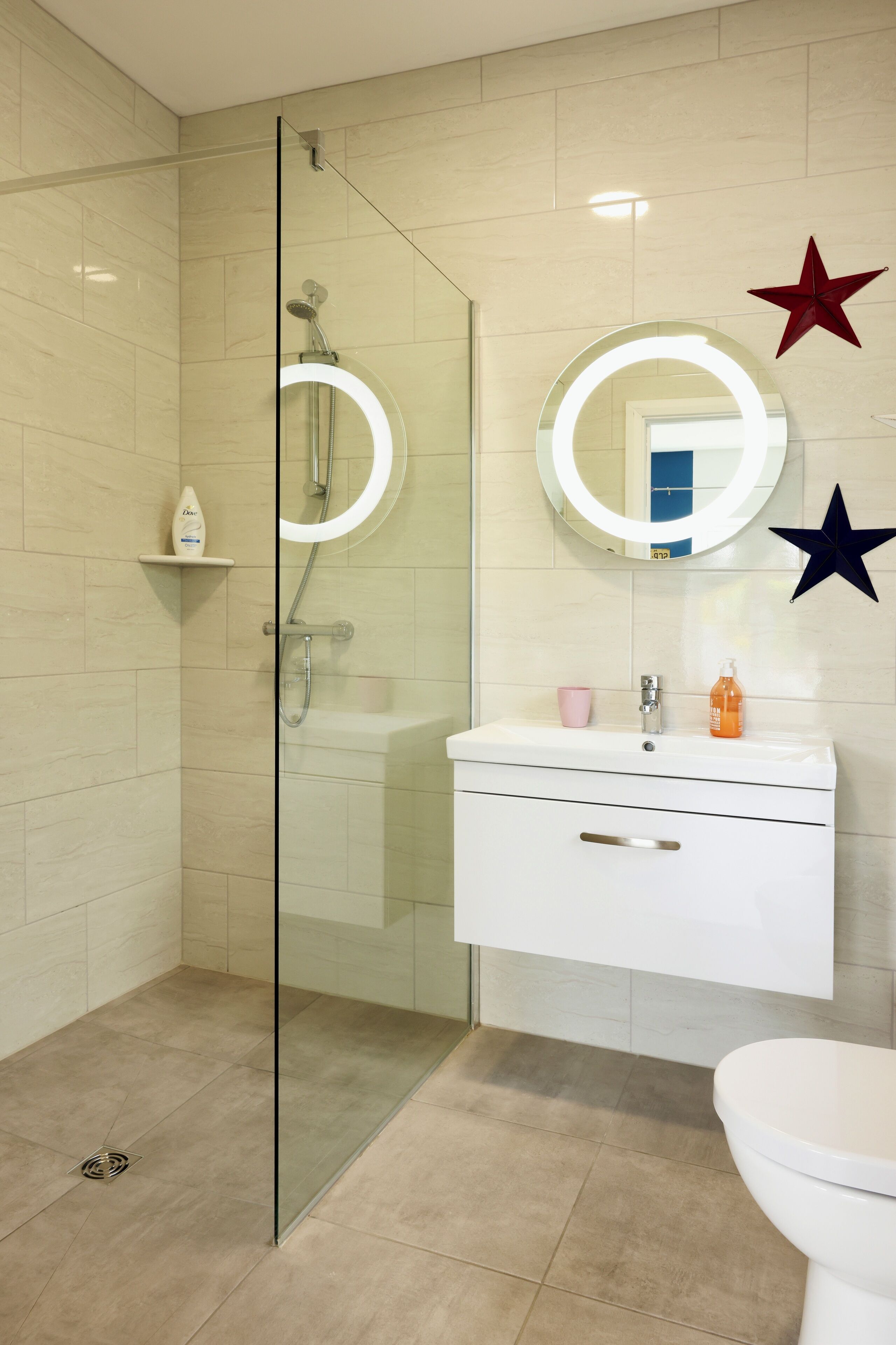 A modern bathroom with a glass-enclosed shower, a white vanity with a mirror, and a toilet.