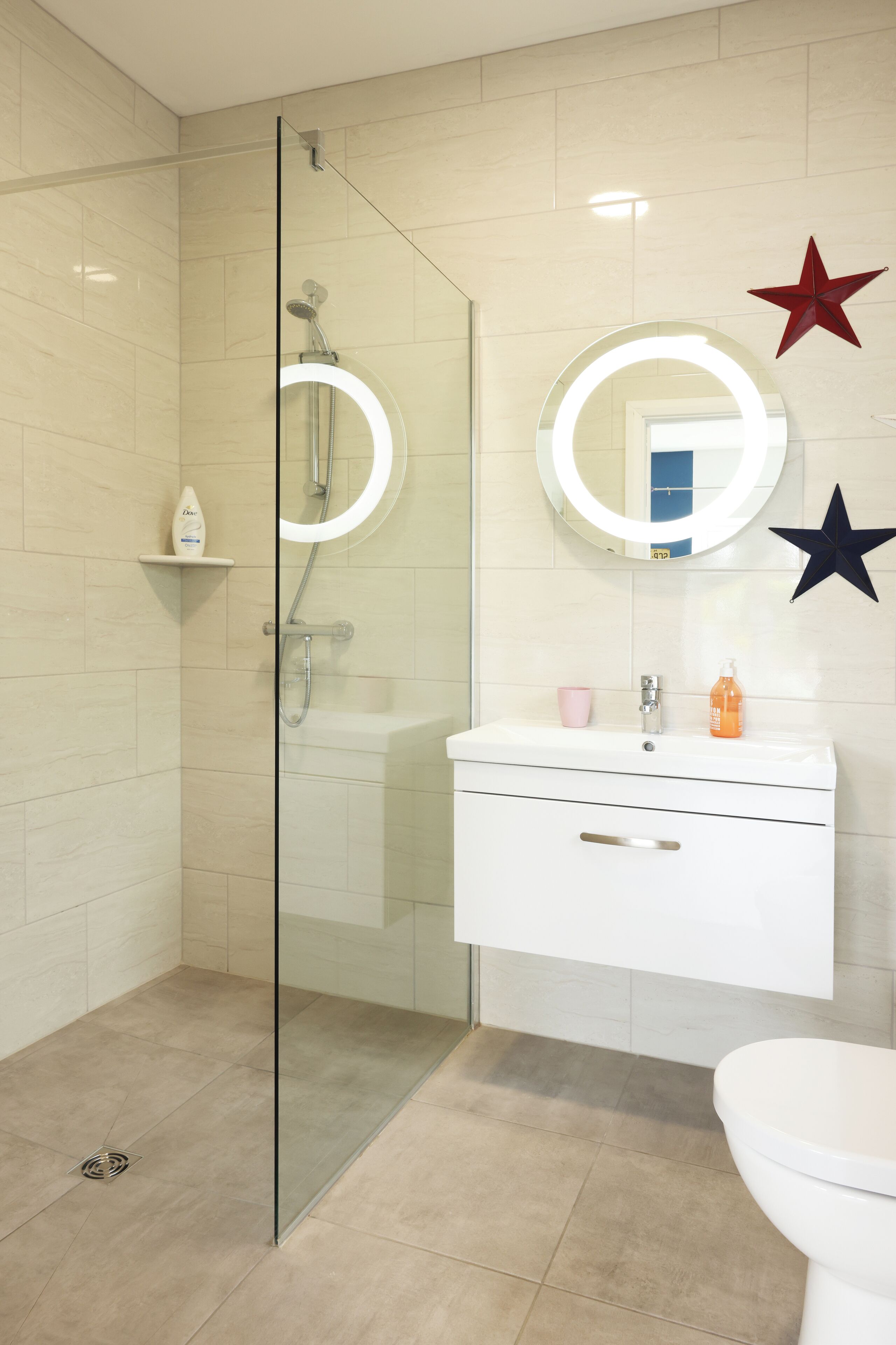 Un baño moderno con cabina de ducha de vidrio, tocador blanco con espejo y inodoro.