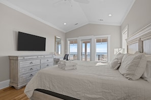 Une chambre à coucher avec un grand lit, une commode, un téléviseur fixé au mur et un balcon avec vue.