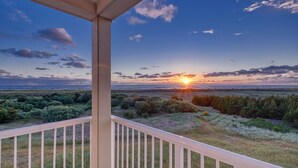 Un balcon offrant une vue sur un coucher de soleil se dégageant sur un paysage plat.
