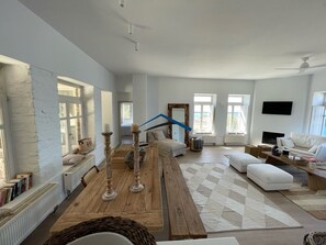 Un salon spacieux avec une table basse en bois, un canapé et un téléviseur fixé au mur.
