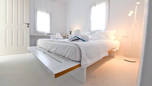 Ein schlicht eingerichtetes Schlafzimmer mit Bett, Nachttisch und Beistelltisch.