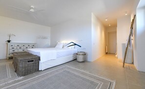 Une chambre à coucher avec un lit, une commode, un panier en osier et une petite table ronde.