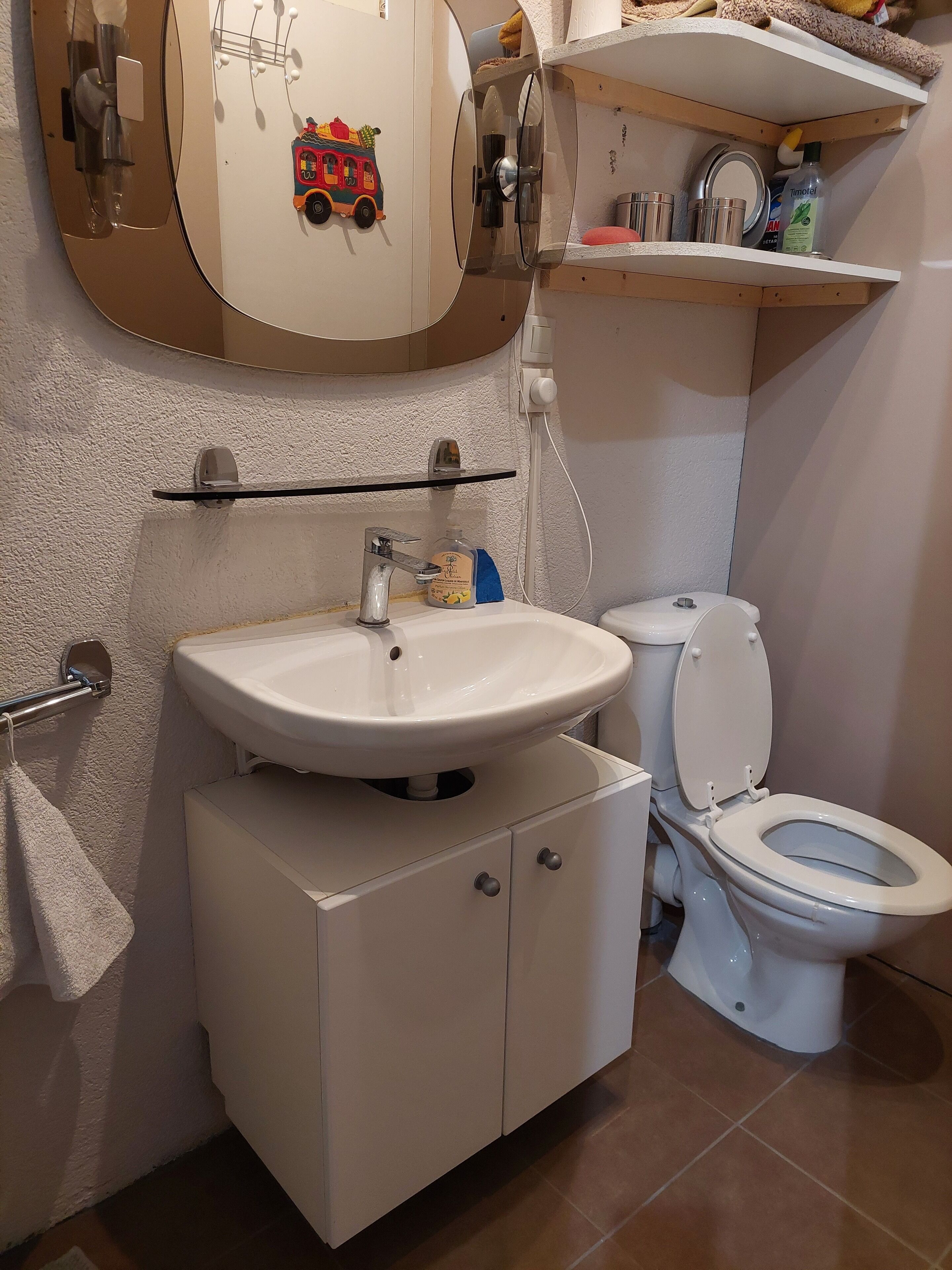 Een badkamer met een wastafel, toilet en een spiegel met decoratieve lijst.