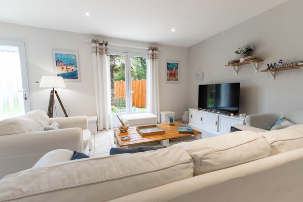 A modern living room with a sofa set, a coffee table, a TV, and a window with curtains.