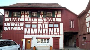 Ein traditionelles Fachwerkhäuschen mit einer Garage, einem kleinen Laden im Erdgeschoss und einem geparkten Auto davor.