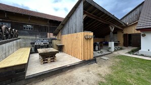 A rustic outdoor area with a barbecue grill, wooden benches, and a pool table. - Idyllischer Bauernhof 1 (Wildensbuch)