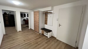 A hallway with wooden flooring, a bench, a mirror, and a door. - Idyllischer Bauernhof 1 (Wildensbuch)