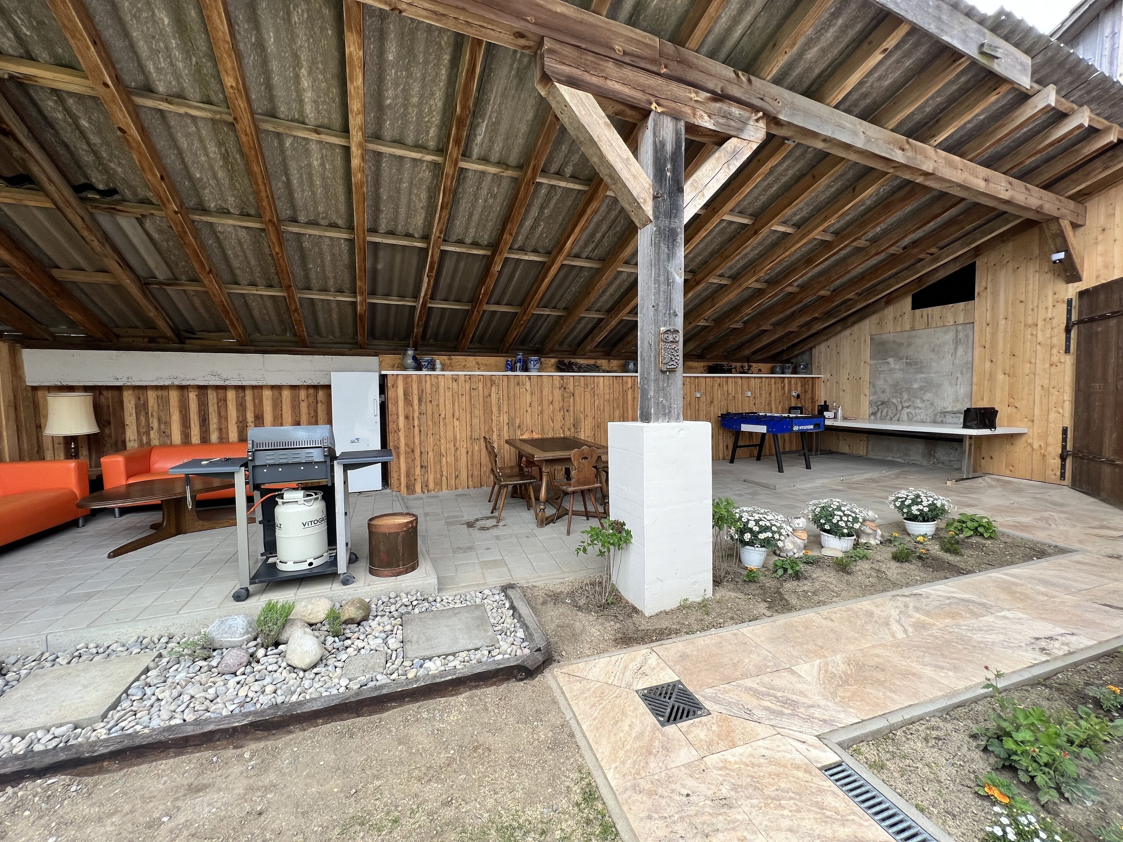 Une terrasse extérieure avec un banc en bois, une table et un barbecue.