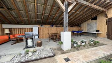 Une terrasse extérieure avec un banc en bois, une table et un barbecue.